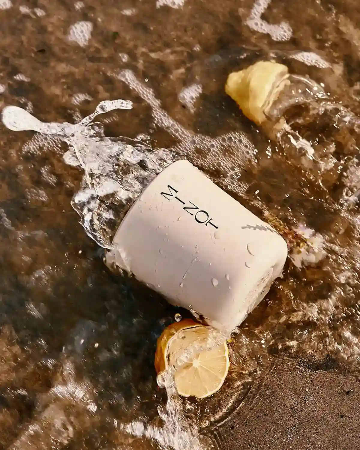 The Cerulean Tide candle is swept up in a salty ocean wave next to lemon slices and jasmine blossoms