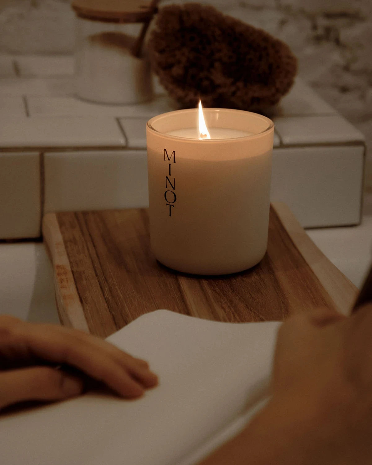 A person journals in the bath by the relaxing light of the Cove lavender and sage scented candle