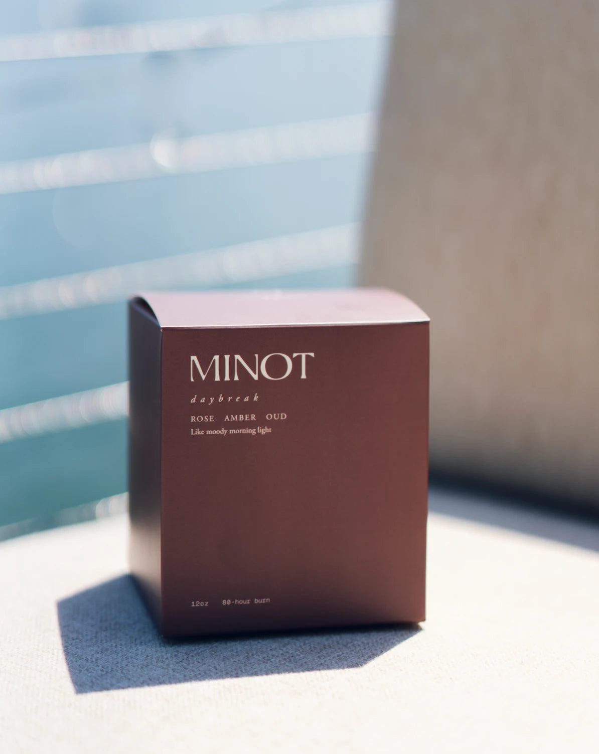 The Daybreak candle's deep reddish-brown box suits its bright, smoky blend of rose, amber, and oud