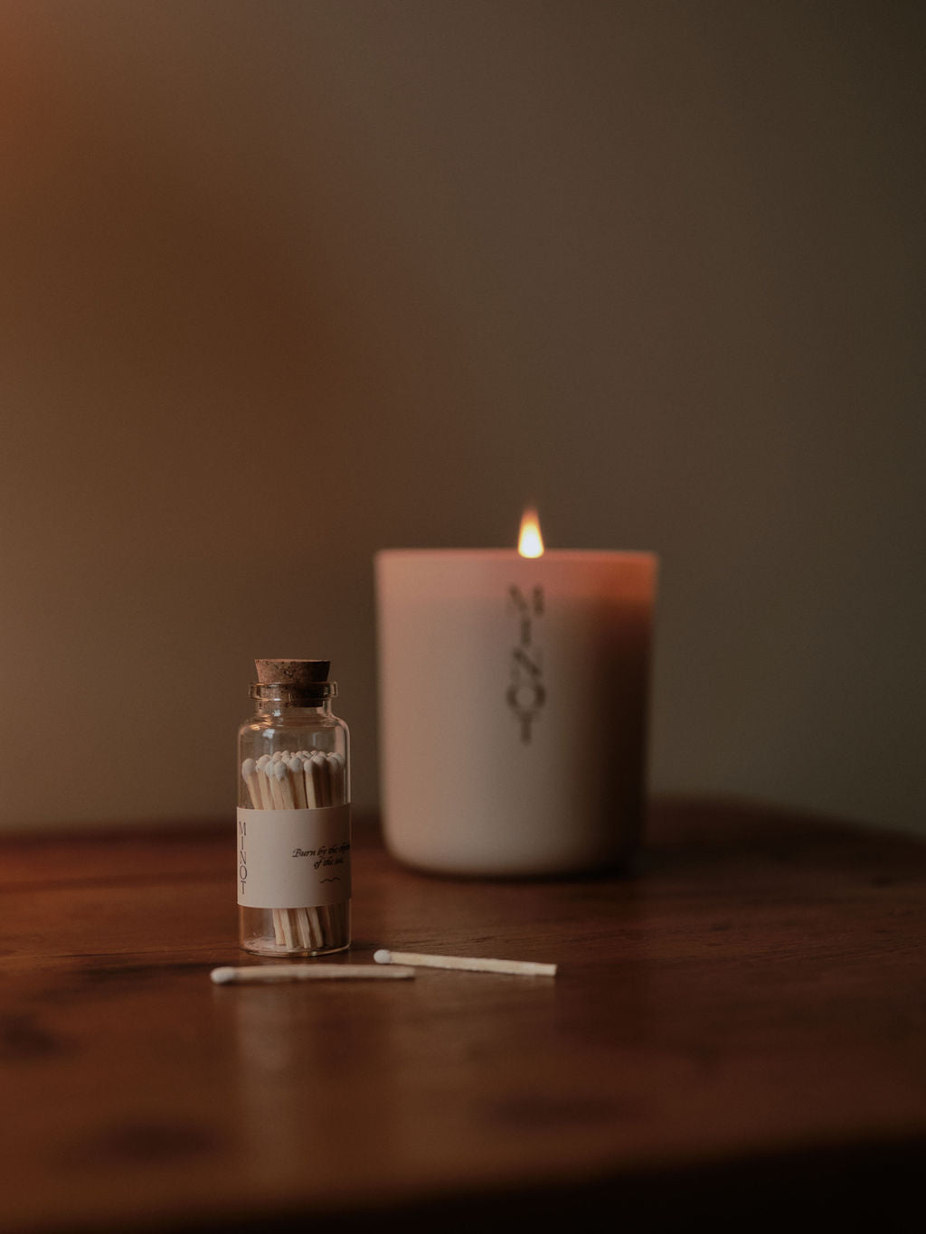 MINOT safety matches in a small glass jar next to a clean-burning soy wax signature candle