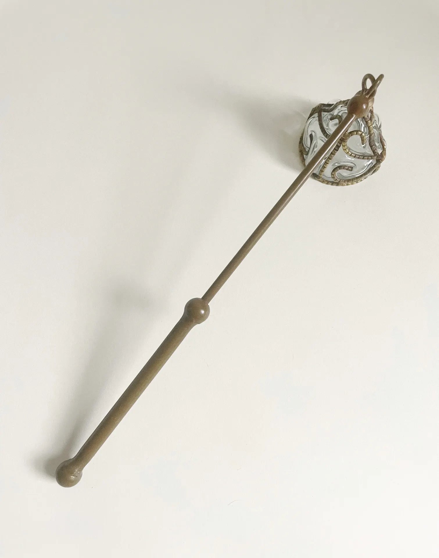 A 12-inch vintage brass candle snuffer with hand-blown glass bell and ornate brass filigree cage