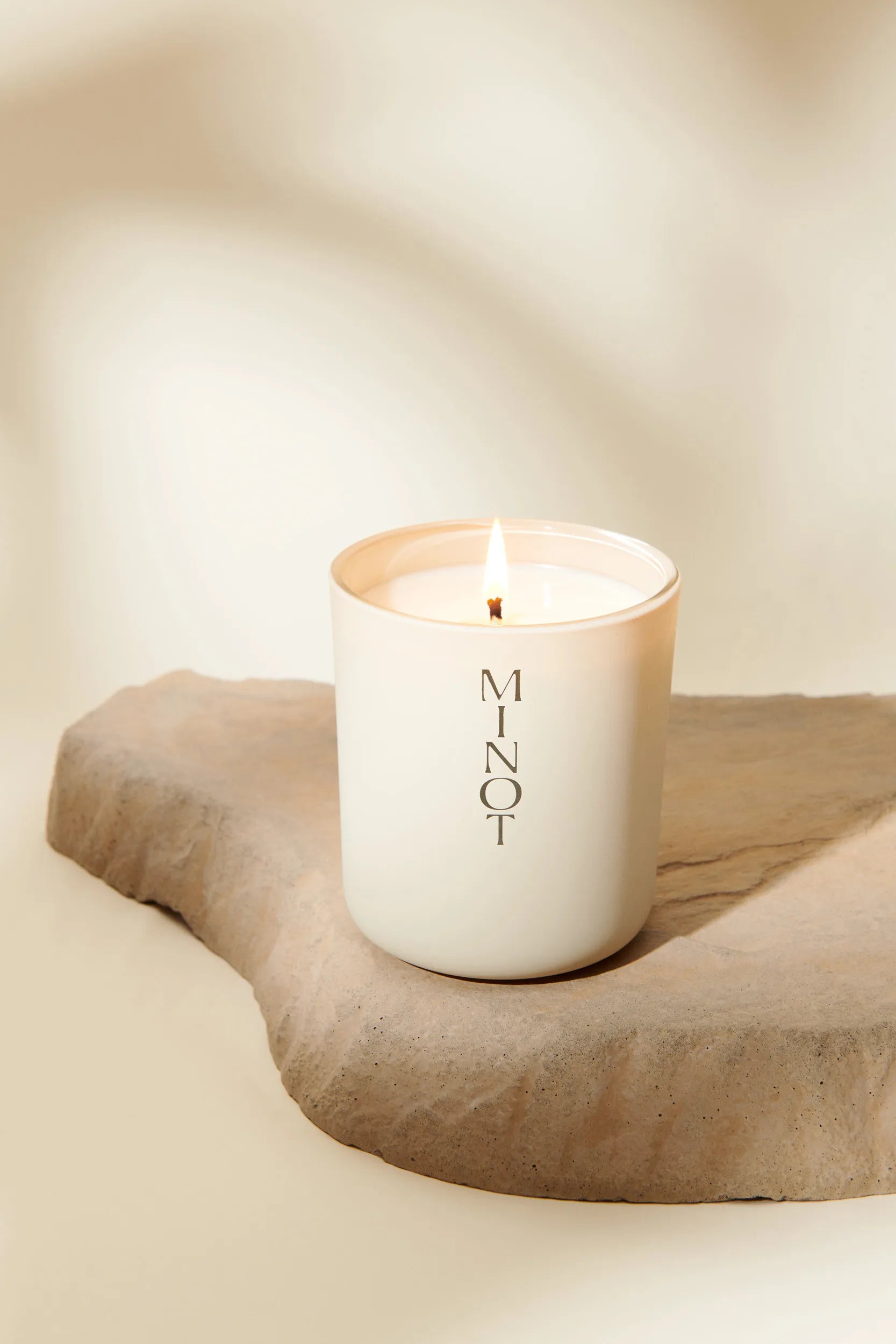 The clean-burning Atmosphere candle is lit, surrounded by scents of almond, coconut, and sandalwood