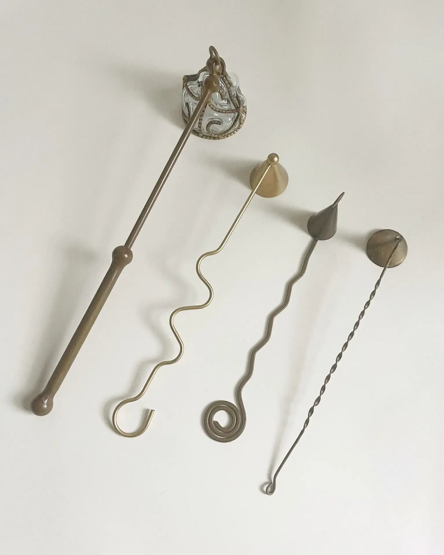 Four handmade, vintage brass candle snuffers in a row from largest to smallest