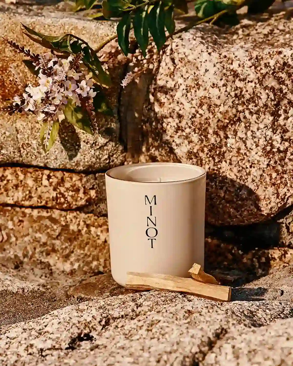 The Cliffwalk candle sits on the side of a stone path next to sandalwood and jasmine blossoms