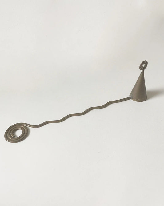A vintage candle snuffer, handmade of brass with a zigzag handle and swirl details on each end