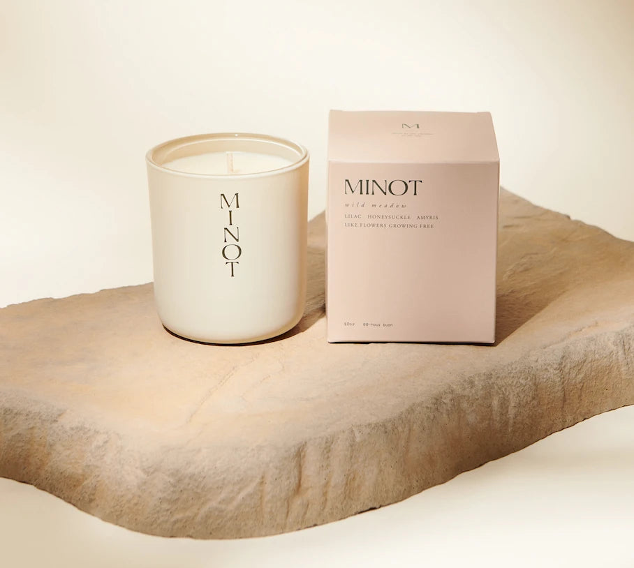 The Wild Meadow candle smells of lilac, honeysuckle, and amyris, and sits next to its blush-pink box