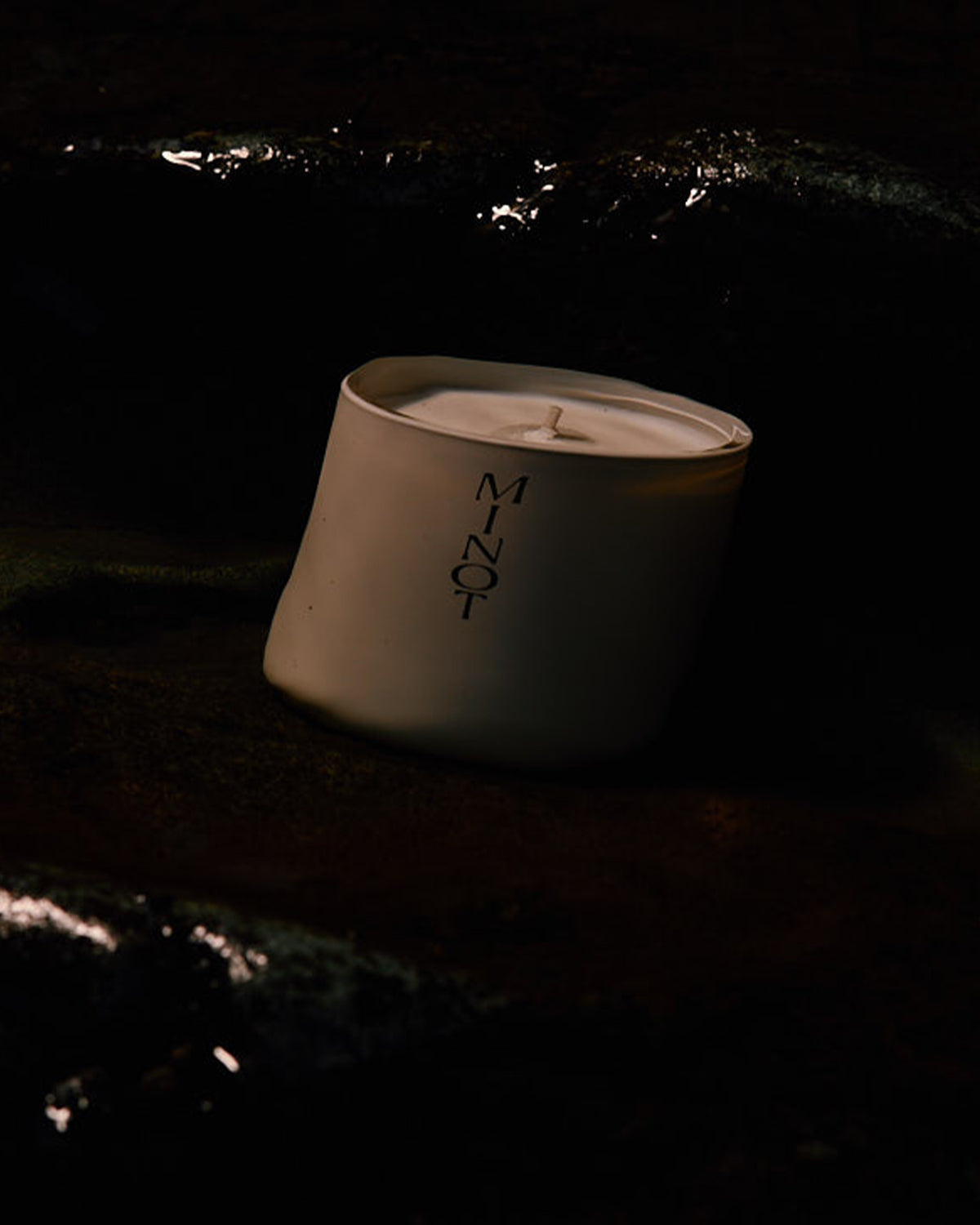 MINOT's minimalist design Dusk candle is barely visible in the dark ocean water